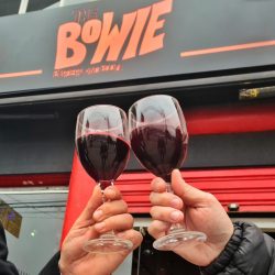 Com uma programação irreverente, karaokê, hambúrgueres de qualidade e outras opções da baixa gastronomia, o TheBowie – Burguers and Booze, localizado no bairro Alto da XV, vem conquistando cada vez mais o público curitibano que frequenta o bar. Agora, o boteco mais comentado do Alto da XV apresenta uma novidade imperdível para o inverno, a “Quinta Jazz”, que consiste em uma seleta programação com os melhores músicos locais do estilo que nasceu nos EUA, no final do século XIX, no berço da cultura afro-americana, na região de Nova Orleans. Além de toda a musicalidade, as noites de quinta-feira também serão marcadas por Open de Vinho, disponível por R$49,90, das 19h às 22h. Serão vinhos tinto, branco e rosê, de rótulos variados. “O The Bowie já virou ponto de encontro para aqueles que gostam de música de qualidade e bons hambúrgueres. Dentro da nossa programação de inverno, agora teremos a Quinta Jazz, com músicos de destaque dentro do estilo musical em Curitiba e região, além de open de vinho para que os clientes aproveitem as noites frias da cidade de forma singular”, comenta Marcelo França, sócio proprietário do TheBowie, sobre a iniciativa de unir a bebida preferida de David Bowie com um dos estilos musicais mais ouvidos pelo artista. Antes de partir, Bowie deixou o surpreendente álbum “Blackstar”, com um rock mais sombrio e toques de jazz experimental e tinha no vinho uma de suas preferências. “O Jazz era um dos estilos musicais preferidos de David Bowie, tanto que ele teve na sua banda um músico pianista de Jazz importante, Mike Garson, e, em suas obras, muitos dos balanços e acordes do Jazz. Além disso era um grande apreciador de vinhos, sendo que ele foi uma das 700 celebridades globais que lançaram rótulos de vinho para campanhas sociais como a ‘Whatever It Takes’”, completa França. Além do open de vinho às quintas-feiras, no cardápio do TheBowie os clientes encontram várias opções de hambúrgueres e petiscos, como o já famoso “Quarter Bowie” (R$17,90), que conta com hambúrguer bovino de 100g, duas fatias de queijo, cebola picada, catchup e mostarda, no pão fofinho e selado; além de opções de petiscos, como a bem pedida porção de pasteis, que sai por R$ 15,90 (06 unidades). Há ainda diversas opções de drinks e chopes que podem ser encontrados no cardápio. O TheBowie - Burgers and Booze fica localizado na Rua Marechal Deodoro, 2.500, no Alto da XV. Acompanhe as novidades por meio das redes sociais oficiais, pelo Instagram @thebowie.cwb e no Facebook @TheBowie. Serviço: The Bowie Burgers and Booze Quinta Jazz com Open de Vinho por R$ 49,90 Endereço: Rua Marechal Deodoro, 2.500 – Loja 1 – Alto da XV (Estacionamento gratuito) Horário: terça a quinta, das 17h à 0h; sexta e sábado, da 17h às 2h Instagram: @thebowie.cwb